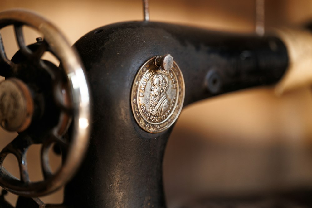 Close-up of a vintage black sewing machine with a round decorative medallion and a wheel on the left